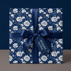 Navy blue floral wrapping paper with white vintage flowers and a luxury satin bow by Wrapped Studios.