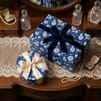 Luxury blue floral wrapping paper by Wrapped Studios on elegant gift boxes with velvet and satin bows.