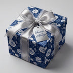 Elegant blue and white floral wrapping paper with a silver ribbon on a wedding gift box by Wrapped Studios.