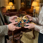 Luxury vintage floral wrapping paper in navy and gold with a satin bow, held by two people. Wrapped Studios.
