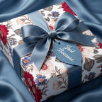 Elegant vintage floral wrapping paper with a dusty blue satin bow on a luxury gift box by Wrapped Studios.