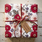 Vintage floral wrapping paper in crimson red and cream, tied with ribbon and twine, by Wrapped Studios.