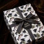 Rustic fishing wrapping paper with trout pattern, grey ribbon, and gift tag by Wrapped Studios.