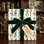 Quirky gift wrapped in unique frog pattern wrapping paper, tied with a dark green velvet ribbon, ideal for a professor's birthday.