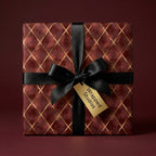 Luxury burgundy wrapping paper with gold diamond pattern and black satin bow by Wrapped Studios.