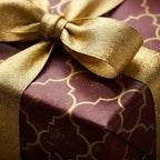 Luxury burgundy and gold geometric Christmas wrapping paper with a metallic bow by Wrapped Studios.