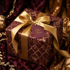 Luxury burgundy and gold wrapping paper with a gold satin bow for holiday gifts, by Wrapped Studios.