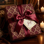 Luxury burgundy and gold Christmas wrapping paper with a satin bow and Joy tag by Wrapped Studios.