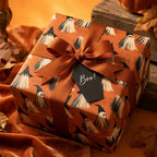 Cute ghost Halloween wrapping paper by Wrapped Studios on a gift box with an orange ribbon and 'Boo!' tag.