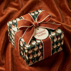 Vintage Santa Claus Christmas gift wrap by Wrapped Studios, tied with a rustic rust ribbon on orange velvet.