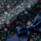 Vintage floral wrapping paper with dark red flowers and a navy blue satin bow by Wrapped Studios.
