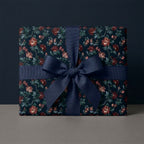 Elegant dark floral wrapping paper with a navy blue ribbon bow by Wrapped Studios.