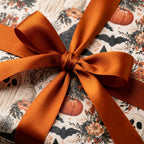 Vintage Halloween gift wrap with pumpkins and bats, tied with a burnt orange satin bow by Wrapped Studios.