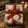 Spooky Halloween wrapping paper with a vintage ghost pattern and rust velvet bow by Wrapped Studios.