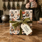 Spooky Halloween gift wrap with ghosts and pumpkins, tied with green velvet ribbon by Wrapped Studios.
