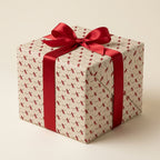 Cream graduation wrapping paper with diploma pattern and red satin bow on a gift box by Wrapped Studios.