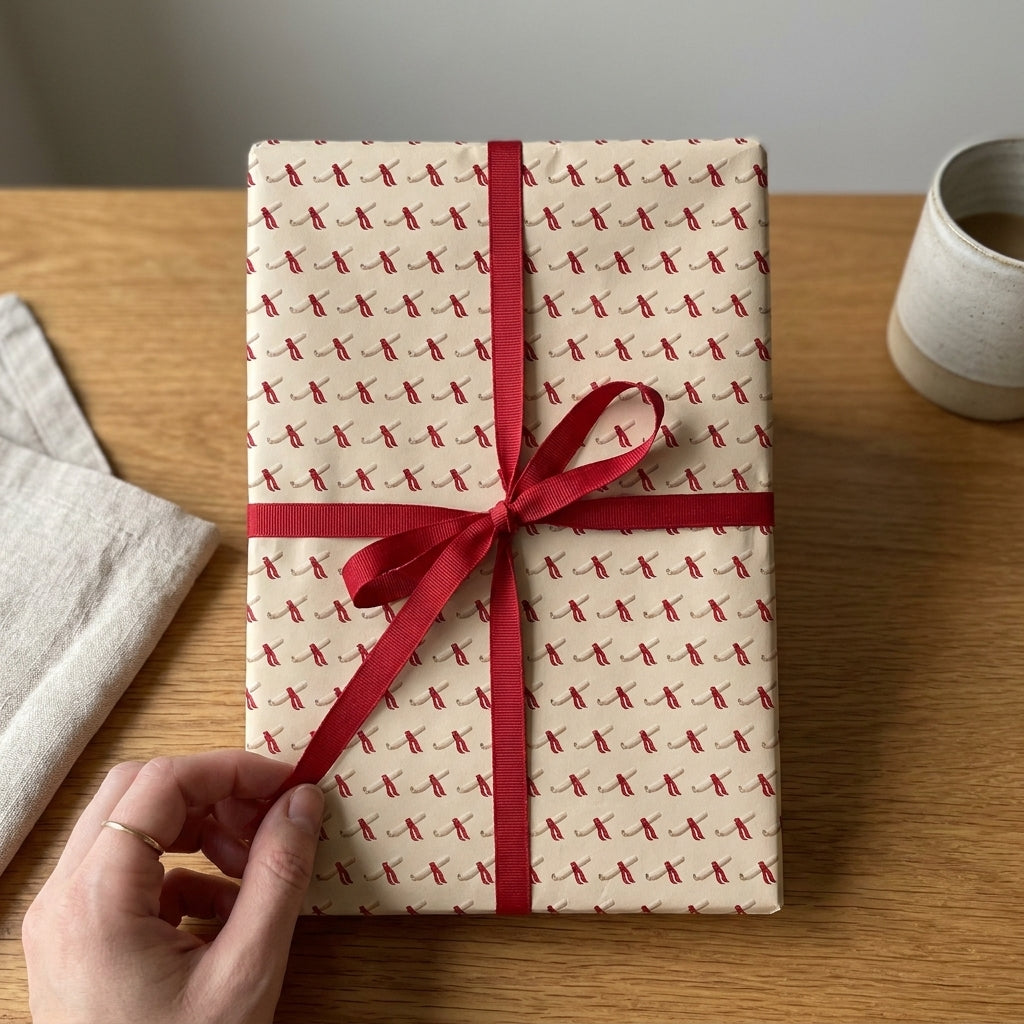 Minimalist scroll pattern wrapping paper with a red ribbon on a gift box by Wrapped Studios.
