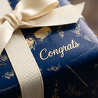 Luxury navy and gold graduation wrapping paper with Congrats text and cream bow by Wrapped Studios.