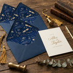 Elegant navy graduation envelope liners with gold caps and announcement card on wood, by Wrapped Studios.