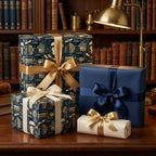Wrapped Studios graduation gift wrap featuring owl and book patterns, tied with elegant satin ribbons on a library desk.
