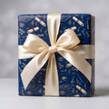 Navy graduation wrapping paper with gold caps, diplomas, and a cream bow by Wrapped Studios.