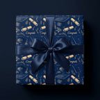 Navy blue graduation wrapping paper with gold caps and diplomas, tied with a satin bow by Wrapped Studios.