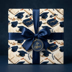 Graduation wrapping paper with navy blue caps and diplomas, tied with a satin ribbon by Wrapped Studios.