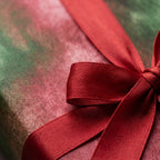 Watercolor red and green Christmas wrapping paper with a luxury satin bow by Wrapped Studios.