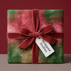 Luxury Christmas wrapping paper in red and green watercolor with velvet ribbon by Wrapped Studios.