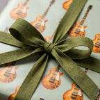 Sage green guitar wrapping paper with an olive ribbon. Music gift wrap by Wrapped Studios.