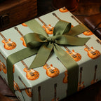 Vintage guitar wrapping paper with an olive green ribbon on a birthday gift box by Wrapped Studios.