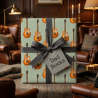 Father's Day guitar wrapping paper with "Dad Rocks" tag and grey ribbon by Wrapped Studios.