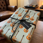 Vintage electric guitar gift wrap paper by Wrapped Studios with a black cord bow and music gift tag.