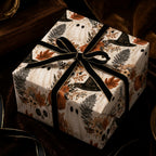 Vintage Halloween wrapping paper featuring ghosts and skulls with a black velvet bow by Wrapped Studios.