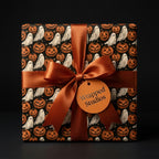 Spooky Halloween wrapping paper with ghosts and pumpkins, tied with an orange bow by Wrapped Studios.