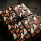 Vintage Halloween wrapping paper with ghosts and pumpkins, tied with black twine by Wrapped Studios.
