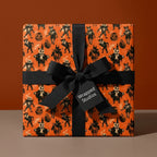 Spooky Halloween wrapping paper with a skeleton pattern and black ribbon, by Wrapped Studios.