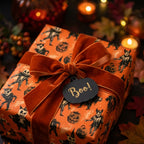 Spooky Halloween wrapping paper with vintage illustrations, a rust velvet bow, and a Boo tag by Wrapped Studios.