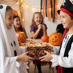Kids in costumes exchange a gift wrapped in pumpkin Halloween wrapping paper. Spooky gift wrap by Wrapped Studios.