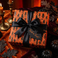 Spooky orange Halloween wrapping paper by Wrapped Studios with black monster pattern and elegant satin bow.
