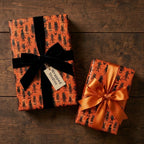Spooky Halloween wrapping paper featuring cute monsters on gifts with velvet and satin bows by Wrapped Studios.