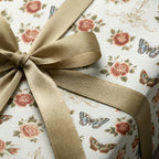 Vintage floral wrapping paper with roses and butterflies, tied with a gold satin ribbon by Wrapped Studios.
