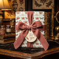 Vintage floral wrapping paper with a dusty rose velvet bow on a gift box, by Wrapped Studios.
