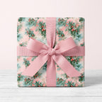 Vintage floral Christmas wrapping paper with pink ribbon bow on a gift box, by Wrapped Studios.