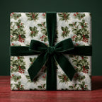 Vintage holly Christmas wrapping paper with a luxury green velvet ribbon on a gift box by Wrapped Studios.