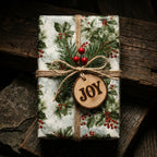 Rustic Christmas gift wrap with vintage holly pattern, twine bow, and wooden JOY tag by Wrapped Studios.