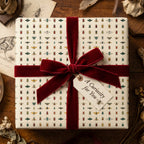 Beetle-themed gift wrapped in ivory wrapping paper with a burgundy velvet ribbon bow.