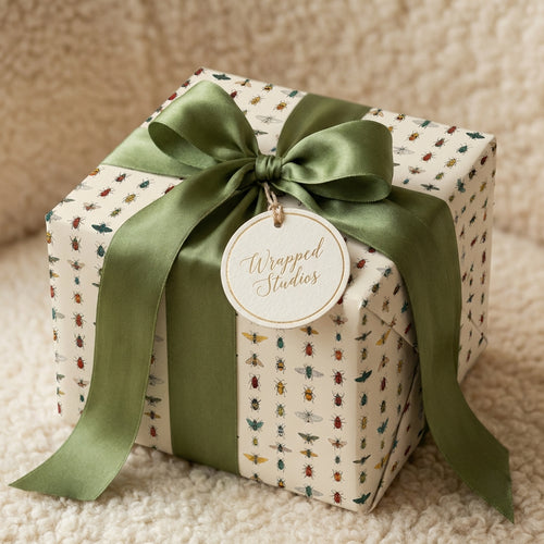 Unique insect-patterned wrapping paper with a green ribbon and tag on a wrapped gift box.