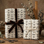 Two presents wrapped in botanical insect print gift wrap with brown velvet ribbon and twine.