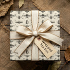 Elegant gift wrapped in entomology-themed paper with cream ribbon, perfect for nature lovers.
